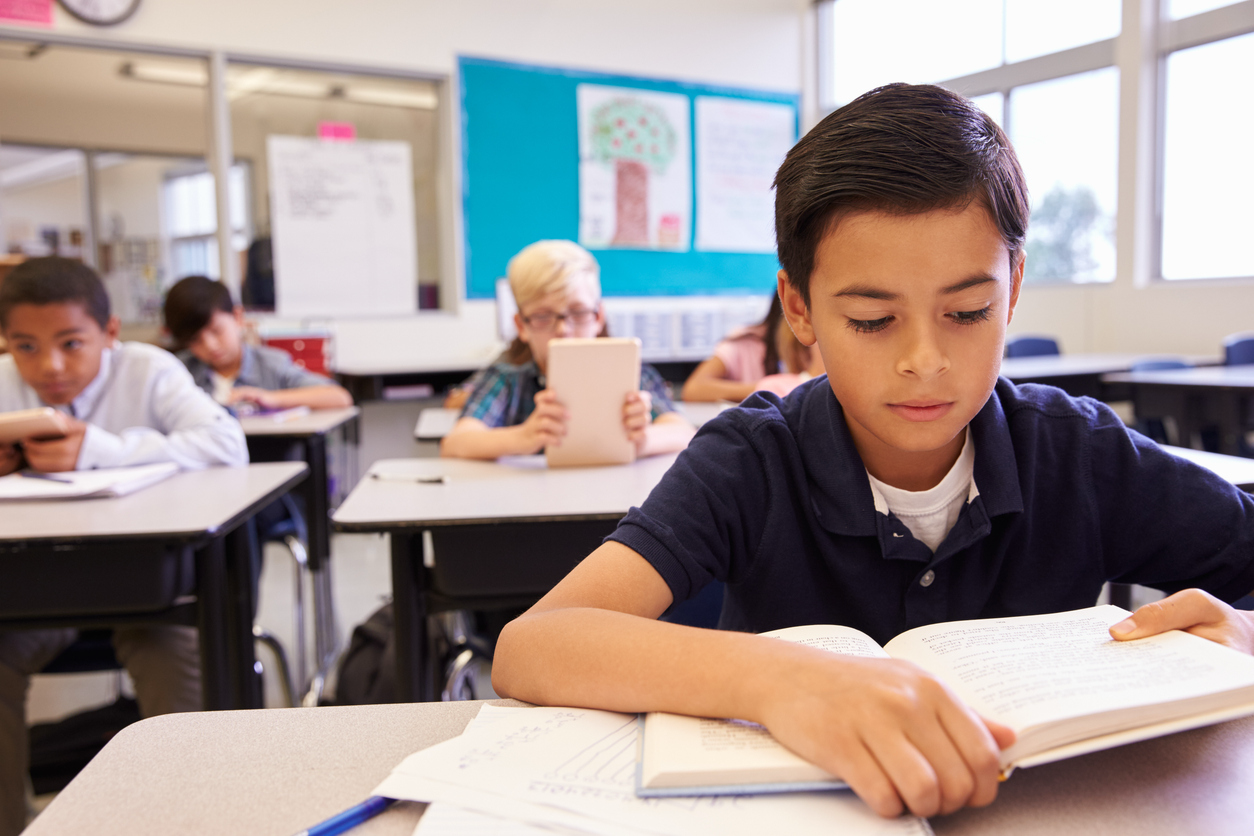 School-aged boy reading at his desk in a classroom, highlighting the visual demands of the school day.